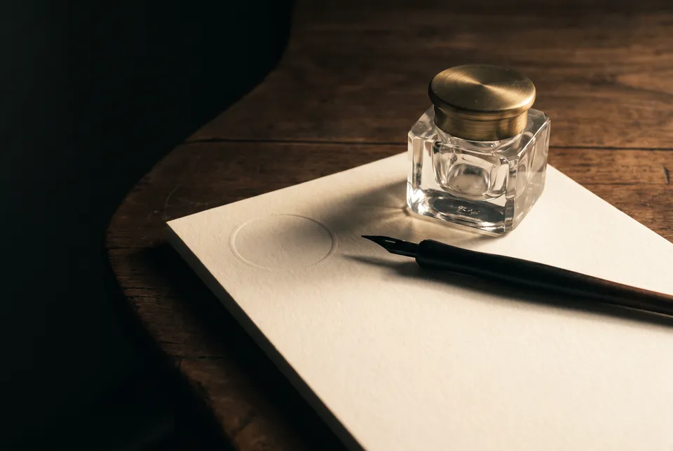 Encrier de verre et porte-plume sur un papier de coton